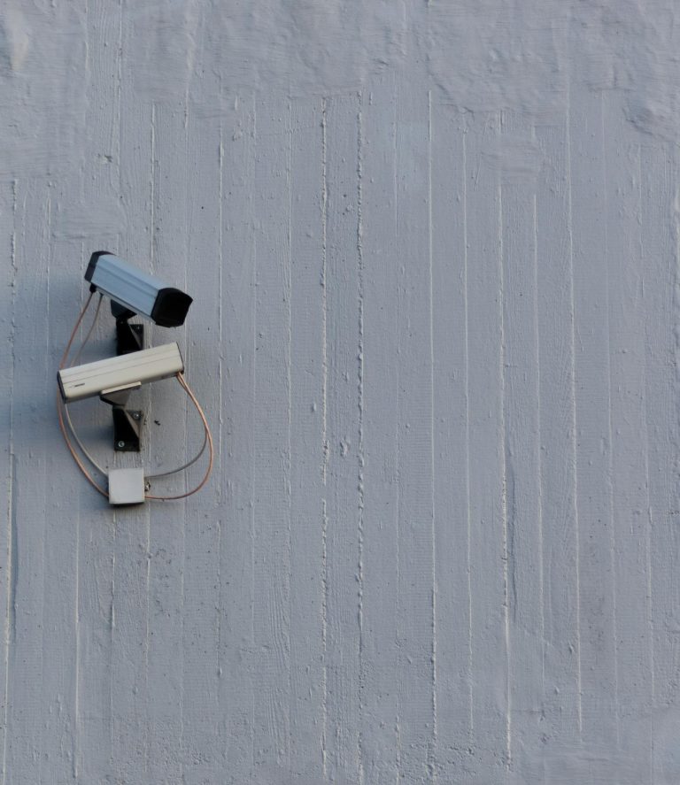 Two surveillance cameras mounted on a wall for security and safety monitoring.